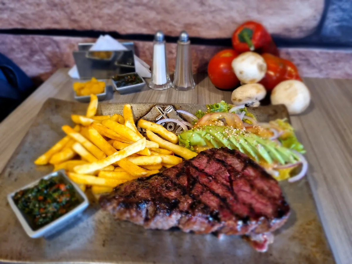 Corte de res a la parrilla con papas y aguacate en tabla de madera