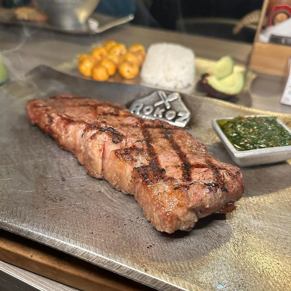 Corte de res a la parrilla con papas y aguacate en tabla de madera