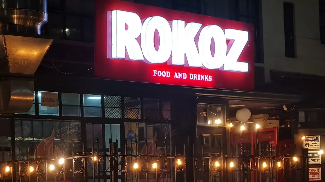 Fachada de Rokoz de noche con el letrero de neón rojo encendido