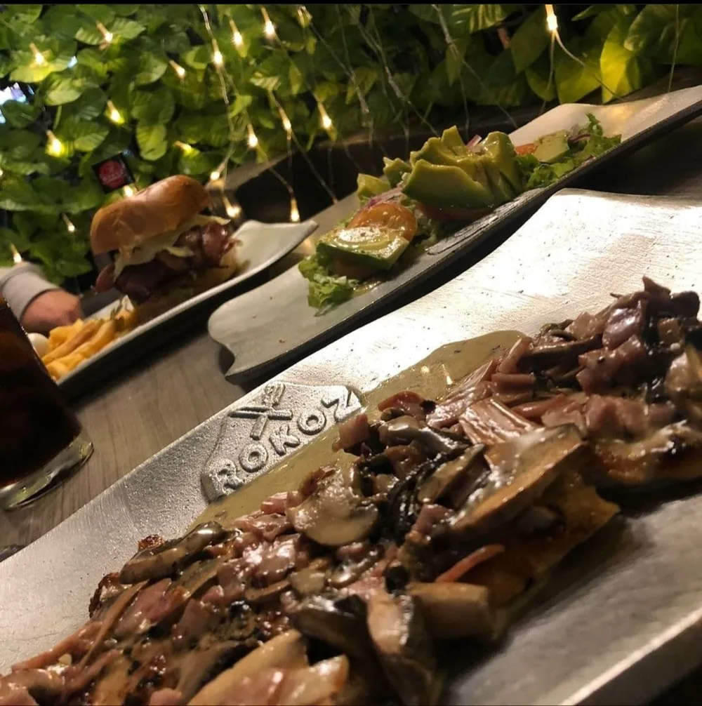 Mesa servida en Rokoz con varios platos y luces cálidas de fondo