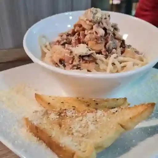 Pasta de la casa servida con pan de orégano