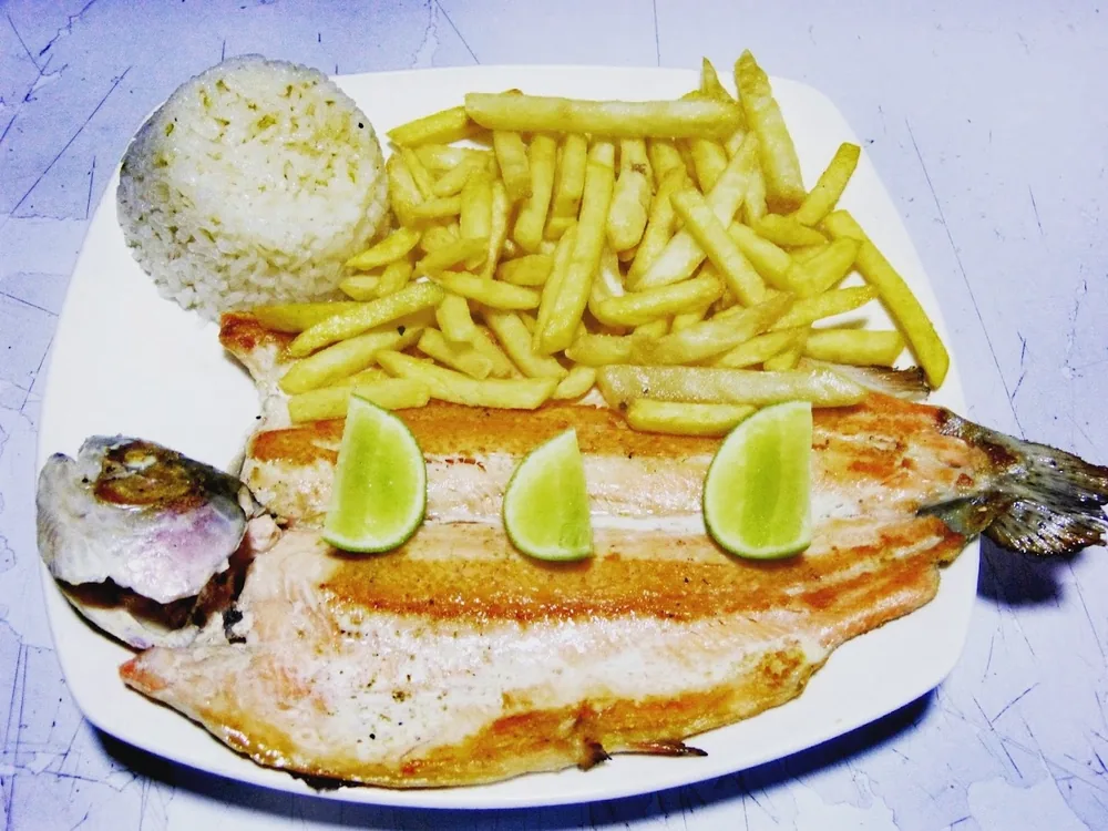 Trucha a la parrilla servida con papas a la francesa y limón